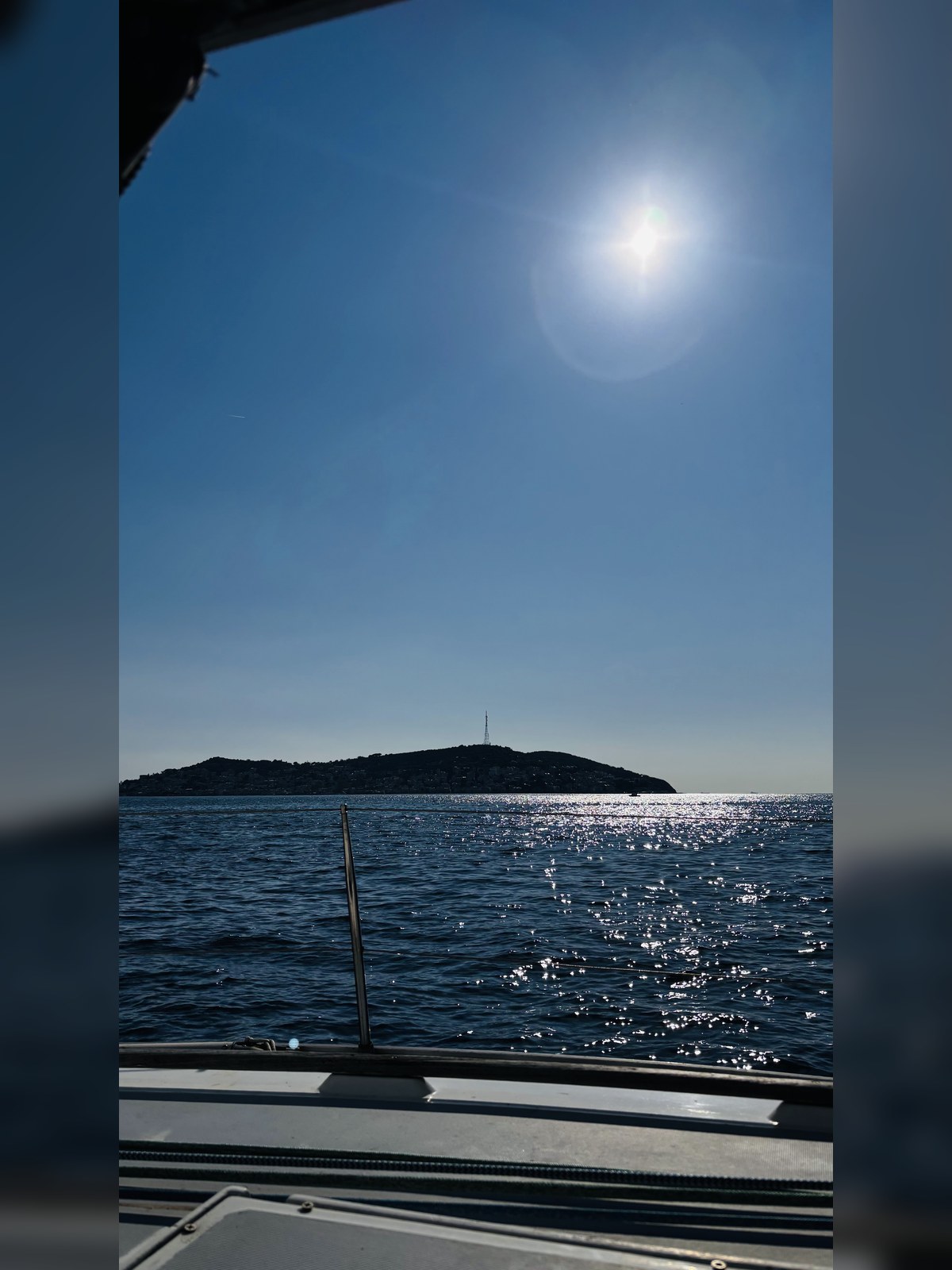 Güneş altında ada silüeti ve denizde yansıma